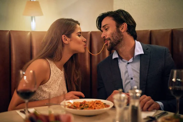 Nada inspira romance como a comida italiana. Tiro de um jovem casal compartilhando espaguete durante um jantar romântico em um restaurante. — Fotografia de Stock