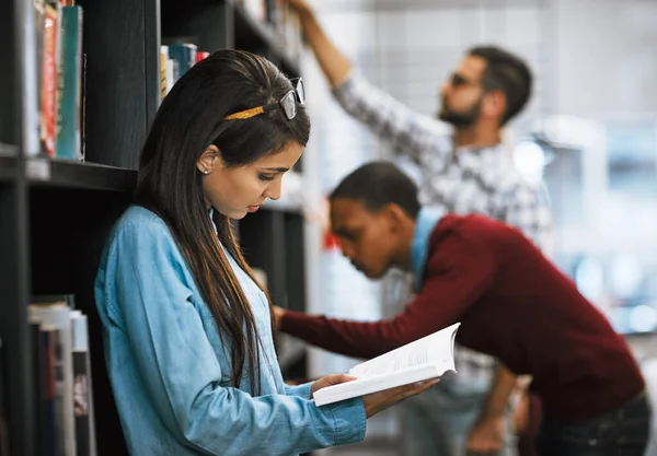 Ich kann dieses Buch nicht weglegen. Aufnahme einer Gruppe junger Studenten, die in einer Bibliothek Bücher zum Lesen aussuchen. — Stockfoto