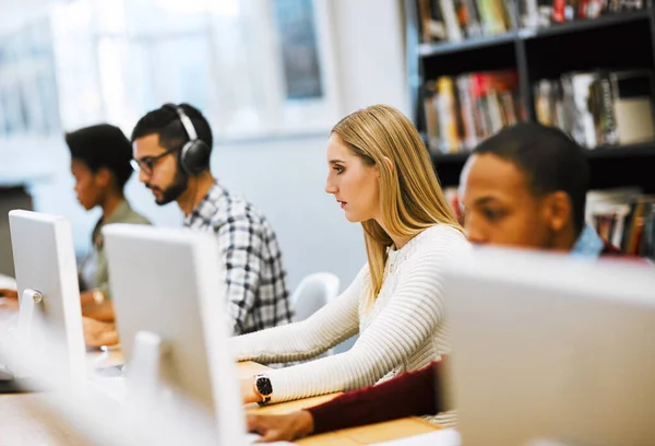 Nous sommes plus préparés que jamais. Prise de vue d'un groupe de jeunes étudiants travaillant sur des ordinateurs et prenant des notes dans une bibliothèque. — Photo