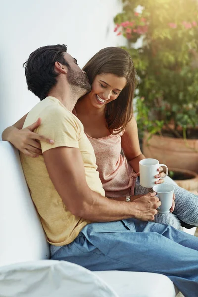 Susurrando amor en su oído. Toma de una feliz pareja joven tomando café juntos en un banco afuera. — Foto de Stock