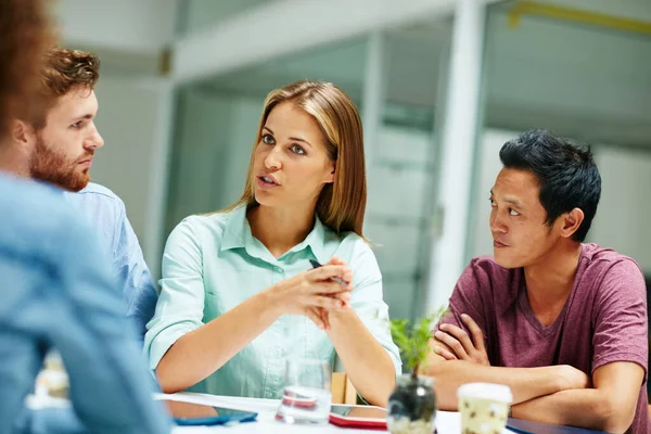 Conversar com a equipa através das ideias dela. Tiro de um grupo de empresários conversando juntos em torno de uma mesa em um escritório. — Fotografia de Stock