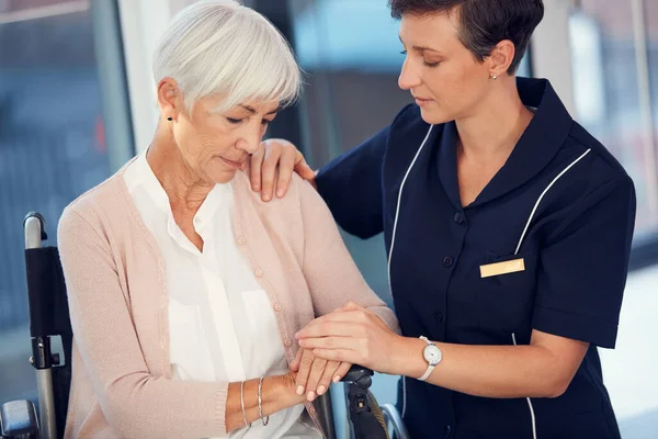 Es wird bald besser werden. Schnappschuss einer jungen Krankenschwester, die eine alte Frau tröstet, die im Rollstuhl in einem Pflegeheim sitzt. — Stockfoto