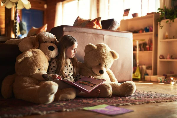 Chcesz, żebym pokazała ci jeszcze raz zdjęcia? Ujęcie małej dziewczynki czytającej książkę z misiami wokół niej.. — Zdjęcie stockowe