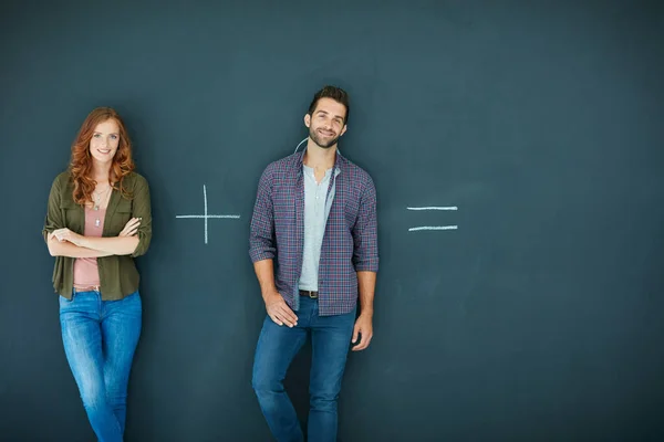 Só pode ser de duas maneiras. Tiro de um jovem casal em pé na frente de um quadro negro com símbolos escritos nele. — Fotografia de Stock