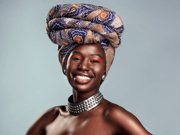 Studio shot of a beautiful young woman wearing a traditional African head wrap against a grey background.