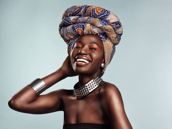 Studio shot of a beautiful young woman wearing a traditional African head wrap against a grey background.