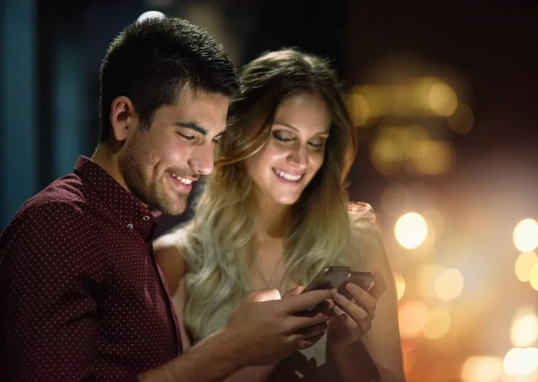 Este é o meu número. Tiro de um jovem casal usando seus smartphones juntos à noite. — Fotografia de Stock