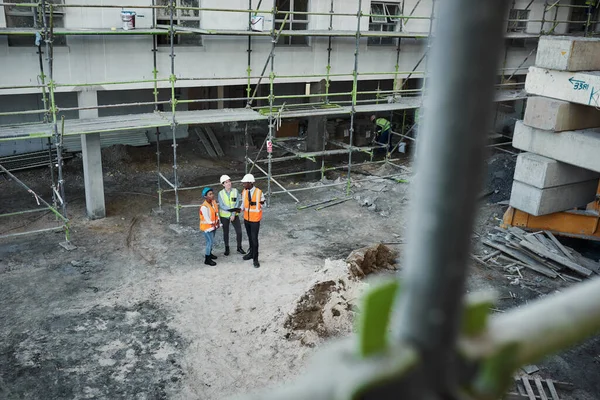 Byggbranschen blomstrar. Skjuten av en grupp byggentreprenörer som har en diskussion under arbetet på en byggarbetsplats. — Stockfoto