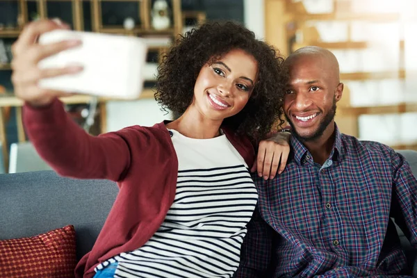 Fånga kvalitetstid med en selfie. Skjuten av ett lyckligt ungt par som tar selfies tillsammans hemma. — Stockfoto
