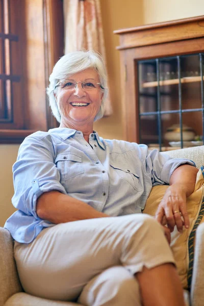 Ζω την καλή ζωή ακόμα και με την συνταξιοδότησή μου. Πορτρέτο μιας ηλικιωμένης γυναίκας χαλαρώνοντας στον καναπέ στο σπίτι. — Φωτογραφία Αρχείου