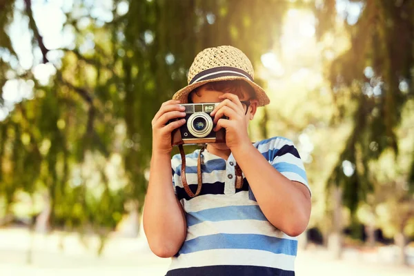 Widzieć świat w nowym świetle. Zdjęcie małego chłopca robiącego zdjęcie z zabytkową kamerą w parku.. — Zdjęcie stockowe