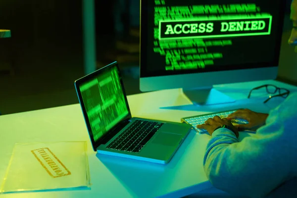 Twoje tajne akta nie są bezpieczne. Strzał nierozpoznawalnego hakera łamiącego kod komputera w ciemności. — Zdjęcie stockowe