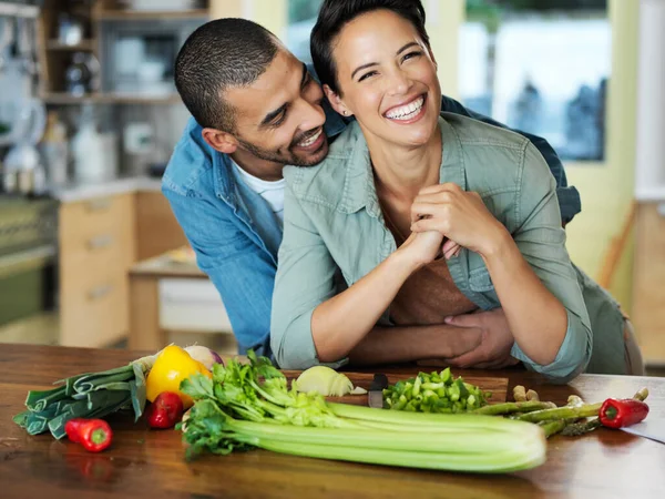 Liefde in hun maaltijd stoppen. Portret van een aanhankelijk jong echtpaar dat samen een maaltijd bereidt in hun keuken. — Stockfoto