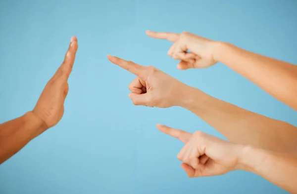 This needs to be put on hold. Shot of an unrecognizable group of people pointing towards hand held out in a stopping gesture against a blue background. — Stock Photo, Image