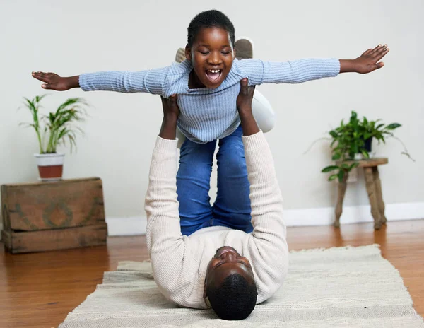 Soy un avión. Foto de una joven feliz vinculándose con su padre en la sala de estar en casa. —  Fotos de Stock