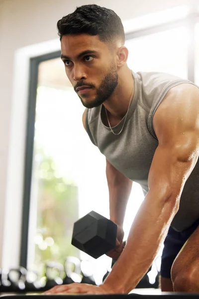 La vida tiene altibajos, los llamamos representantes. Un disparo de un joven haciendo ejercicio con pesas en un gimnasio. — Foto de Stock