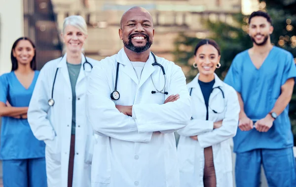 A sua saúde é a nossa prioridade. Tiro de um grupo de médicos de pé de braços cruzados na cidade. — Fotografia de Stock