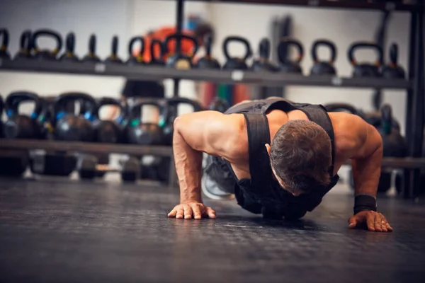 Los fuertes no muestran miedo. Tiro de cuerpo entero de un joven guapo haciendo flexiones mientras hace ejercicio en el gimnasio. —  Fotos de Stock