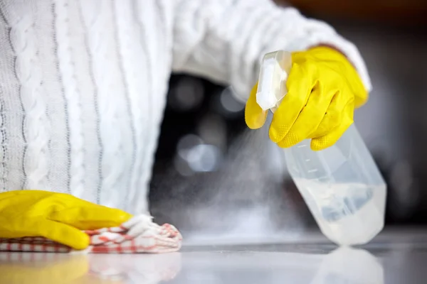 Gebruik altijd een sterk ontsmettingsmiddel. Schot van een vrouw spuit haar keuken teller om het schoon te maken. — Stockfoto