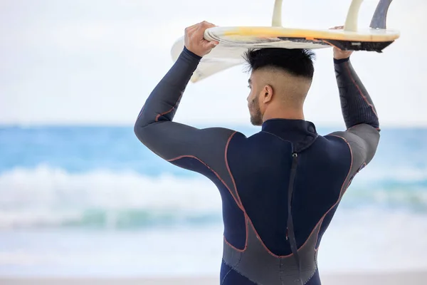Les eaux sont parfaites. Plan d'un jeune homme tenant une planche de surf à la plage. — Photo