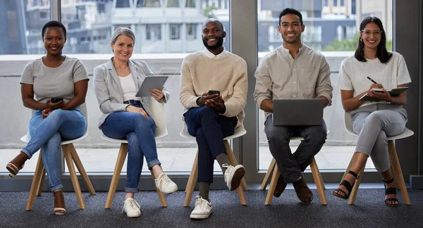 Che cosa porti in tavola? Girato di un gruppo di uomini d'affari che utilizzano dispositivi wireless in attesa di un'intervista. — Foto Stock