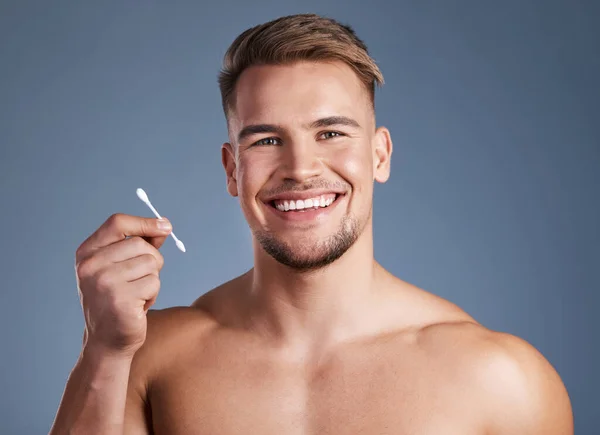 This is what youll need. Shot of a man holding up a earbud while standing against a grey background. — Stock Photo, Image