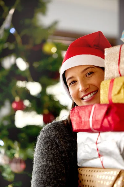 クリスマスは交わり、ごちそう、与え、受け取ることを意味する。家で贈り物を積んでいる若い女性のショット. — ストック写真