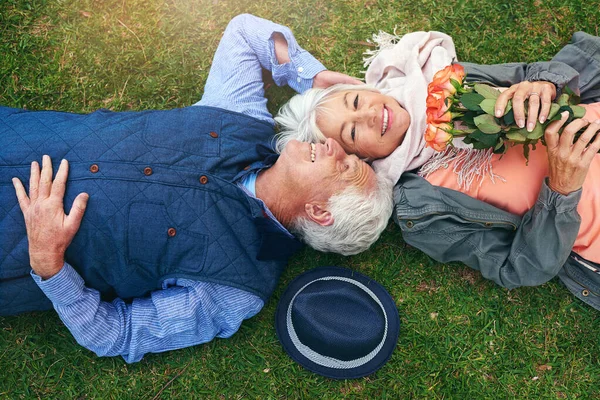 Han köper rosor åt mig. Porträtt av ett äldre par njuter av dagen tillsammans i en park. — Stockfoto