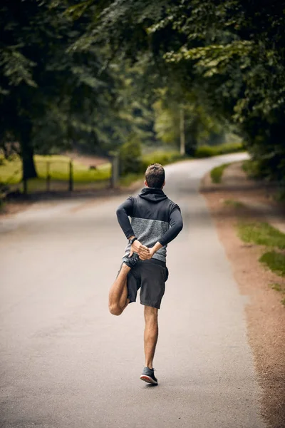 Põe-te em forma. Tiro de um homem esportivo começando sua rotina de exercícios com exercícios de alongamento. — Fotografia de Stock