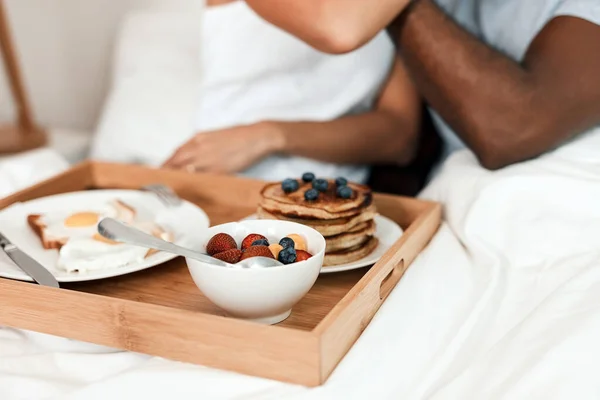 Snídaně do postele se podává. Shot z nerozpoznatelný pár těší snídani v posteli spolu doma během dne. — Stock fotografie