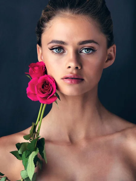 Two natural beauties in their element. Studio shot of an attractive young woman posing next to a couple of beautiful pink roses. — Stock Photo, Image