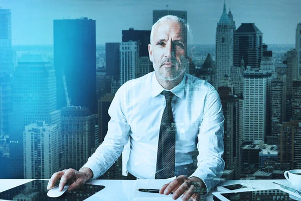 Enfréntate al mundo de los negocios. Retrato de un hombre de negocios maduro usando una computadora en una oficina moderna superpuesta a un paisaje urbano. —  Fotos de Stock