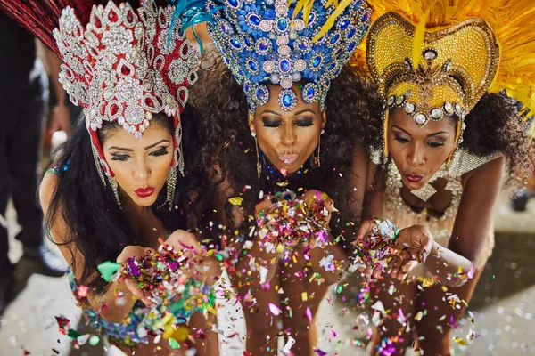 Difundiendo su magia durante la noche. Tiro de bailarines de samba soplando confeti de sus manos mientras actuaban en un carnaval. —  Fotos de Stock