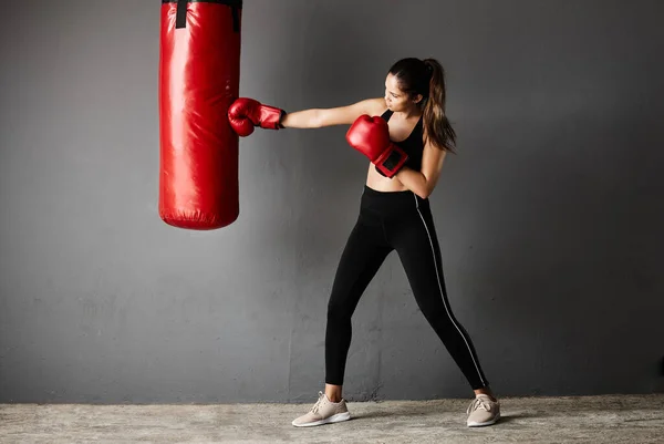 Powerful punch. Full length shot of an attractive young female boxer training in the gym. — Stock Photo, Image