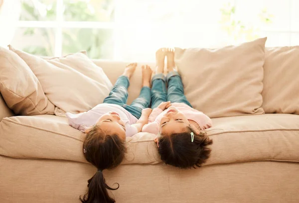 Jolie intrigue. Prise de vue de deux sœurs collant sur le canapé à la maison. — Photo