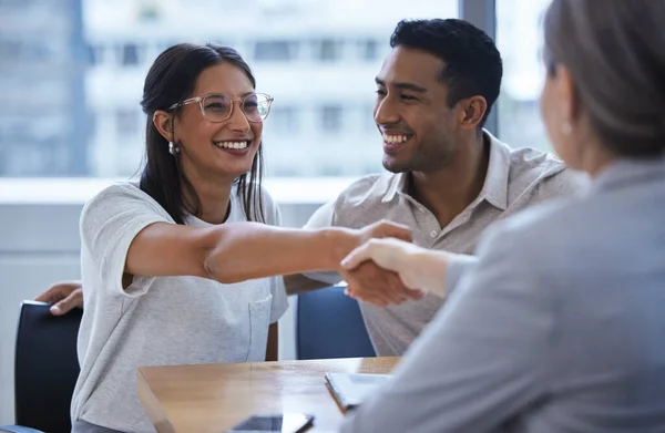 Ella es el mejor día de mi vida. Fotografía de una joven pareja compartiendo un apretón de manos con un consultor de su reunión para discutir el papeleo en una oficina. —  Fotos de Stock