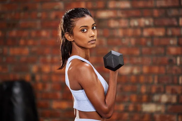 Estoy trabajando en convertirme en la mejor versión de mí mismo. Foto de una joven deportista haciendo ejercicio con pesas en el gimnasio. —  Fotos de Stock