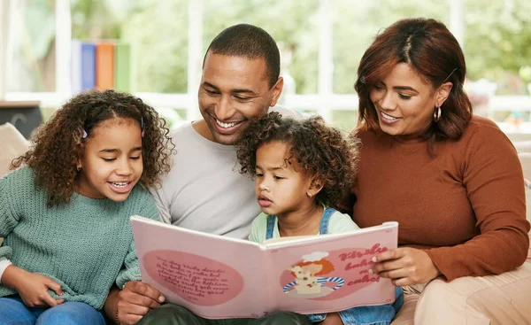 Estas páginas cuentan una historia mágica. Fotografía de una joven familia leyendo un libro en casa. — Foto de Stock