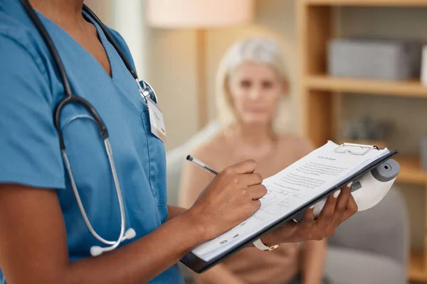 Ce médecin fait des livraisons à domicile. Prise de vue d'un médecin remplissant un questionnaire lors d'une consultation avec une femme âgée à la maison. — Photo