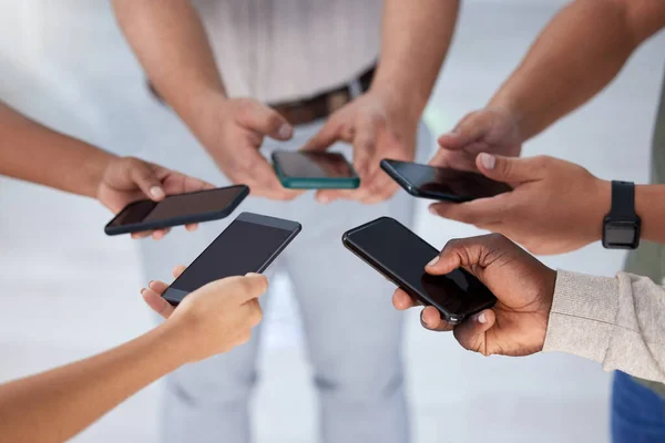 Eine Verbindung, die zum Erfolg führt. Nahaufnahme einer Gruppe von Geschäftsleuten, die ihre Handys synchron in einem Büro benutzen. — Stockfoto