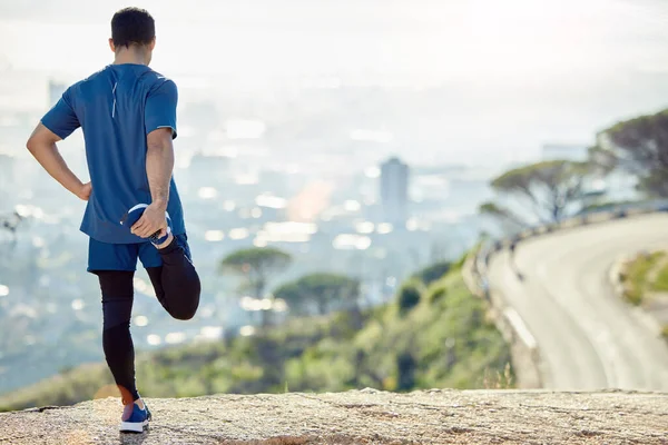 Una palestra all'aperto con vista. Colpo completo di un uomo irriconoscibile in piedi da solo e che si estende durante il suo allenamento all'aperto. — Foto Stock