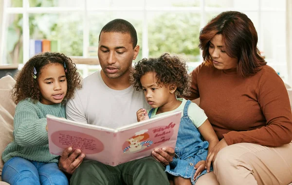 La familia es un regalo que dura para siempre. Fotografía de una joven familia leyendo un libro en casa. — Foto de Stock