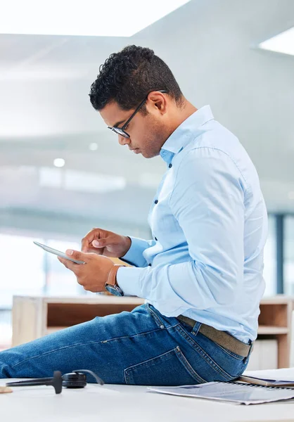 A enviar e-mails de clientes. Tiro de um belo jovem empresário sentado sozinho em seu escritório e usando um tablet digital. — Fotografia de Stock