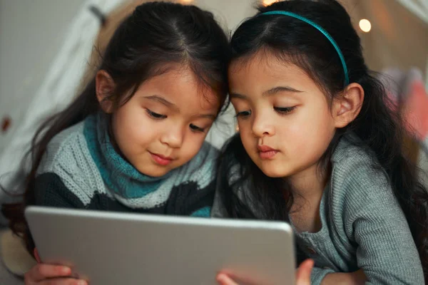 Amano guardare le cose insieme. Girato di due sorelle utilizzando un tablet digitale a casa. — Foto Stock