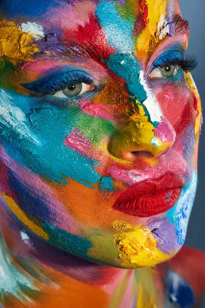 Mantente colorido. Foto de estudio de una joven posando con pintura multicolor en la cara. —  Fotos de Stock