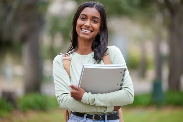 É difícil não sorrir com um futuro brilhante pela frente. Retrato de uma jovem mulher carregando seus livros escolares fora na faculdade. — Fotografia de Stock