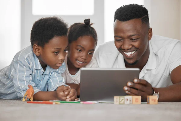 Helpen met huiswerk op een leuke manier. Foto van een vader met behulp van een digitale tablet met zijn zoon en dochter thuis. — Stockfoto