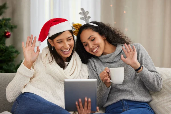 Bu yıl Noel 'i biraz farklı kutluyoruz. Noel zamanı dijital tablet üzerinde video görüşmesi yaparken iki arkadaşın yan yana oturması.. — Stok fotoğraf