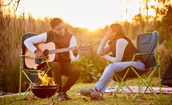 모닥불 주위 생활이 더 낫다. 밖에서 캠핑중에 아내에게 기타를 연주하는 남자의 모습을 찍은 사진.. — 스톡 사진