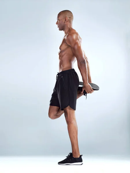 Tartsd meg az egyensúlyod. Stúdió lövés egy sportos fiatalember csinál stretching gyakorlatok, miközben pózol a szürke háttér. — Stock Fotó